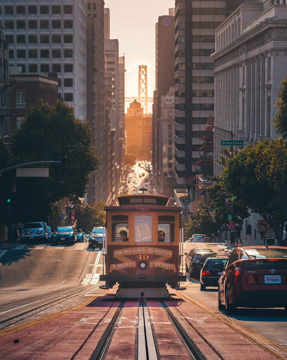 A cable car climbing a sunlit San Francisco street at dusk